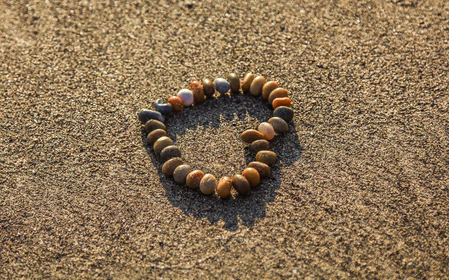 Сердце из мелкий морских камей на песке 