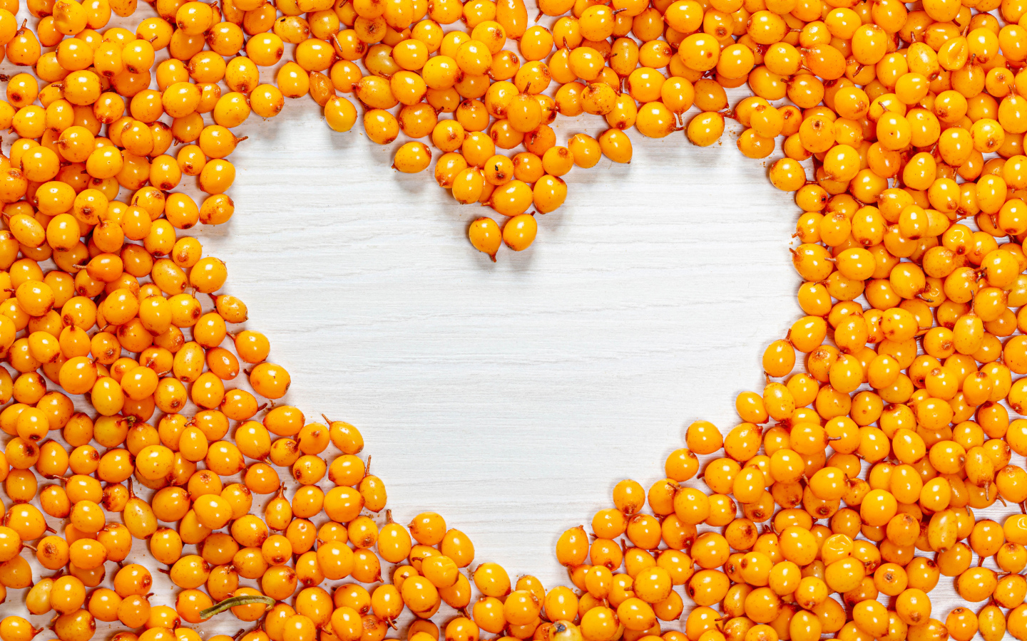 Сердце из ягод облепихи на столе 
