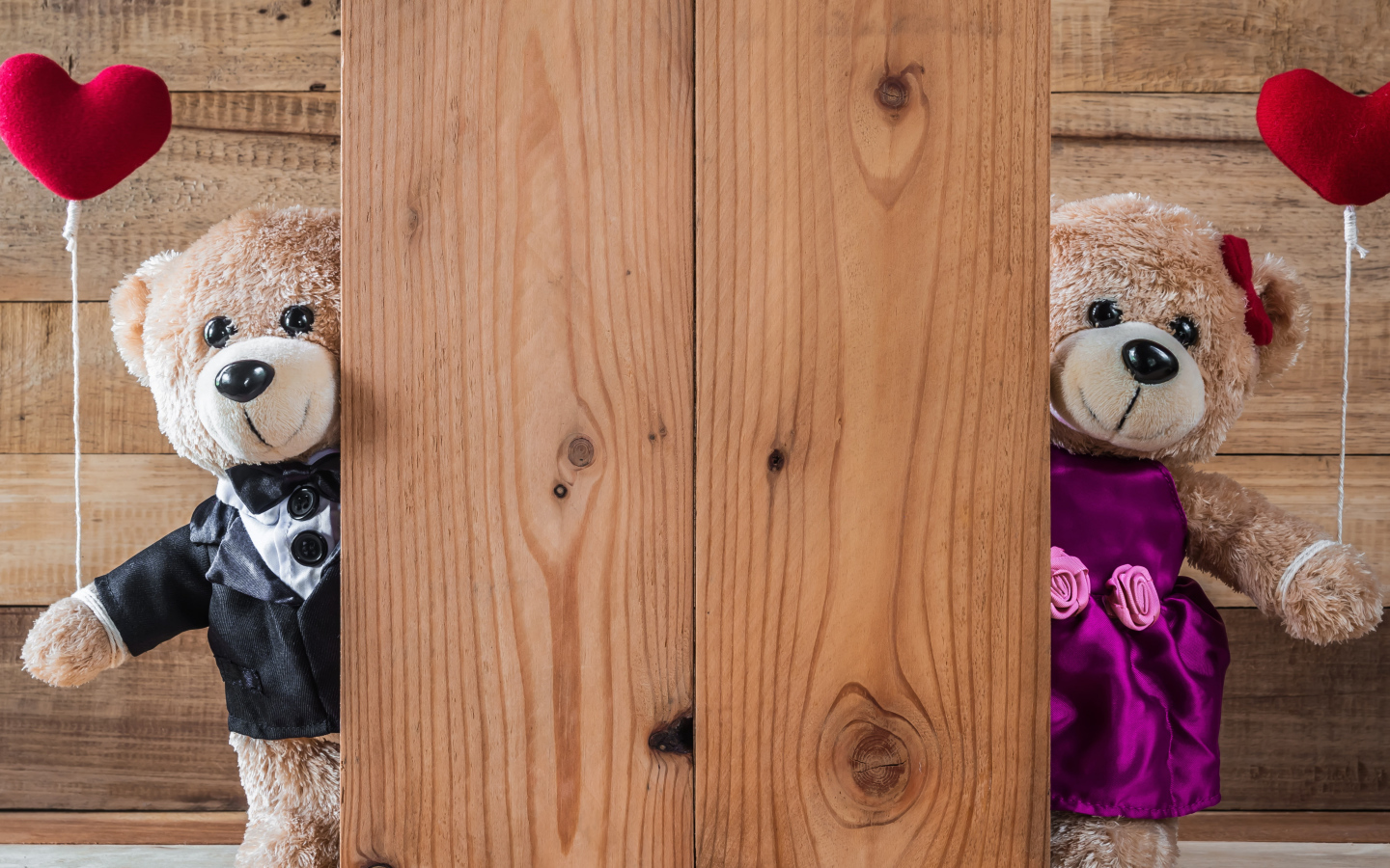 Два плюшевых медведя с сердечками у стены