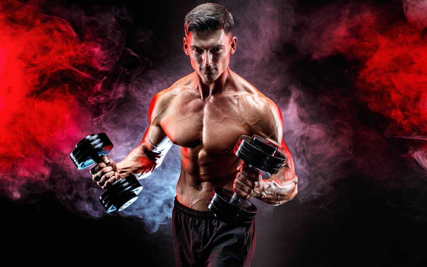 Мускулистый мужчина с гантелями в руках на черном фоне с дымом