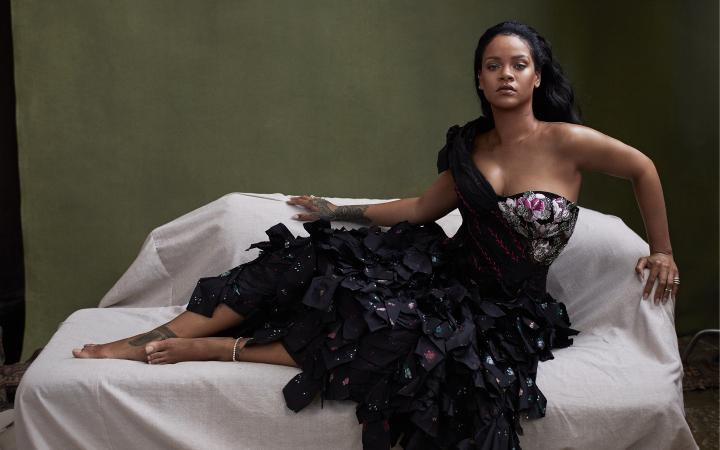 Singer Rihanna in a black dress on the couch