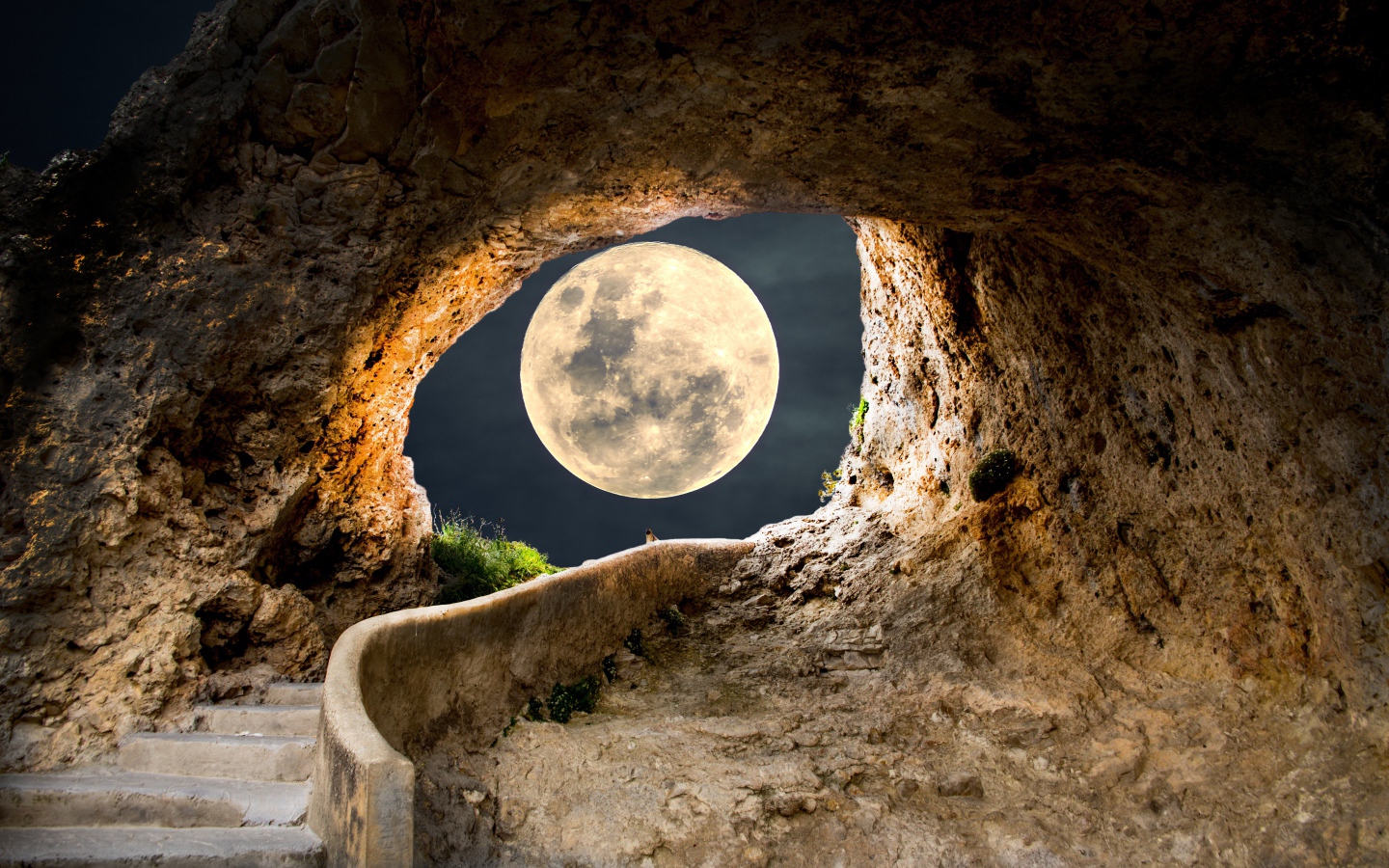 A large white moon illuminates the passage to the cave