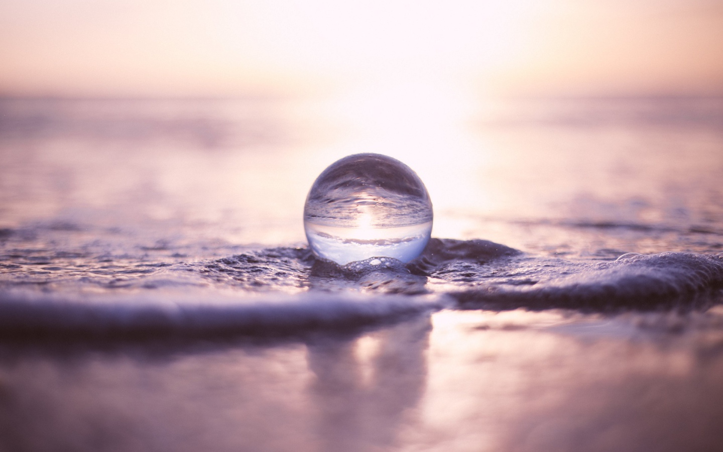Прозрачный стеклянный шар лежит на пене в море
