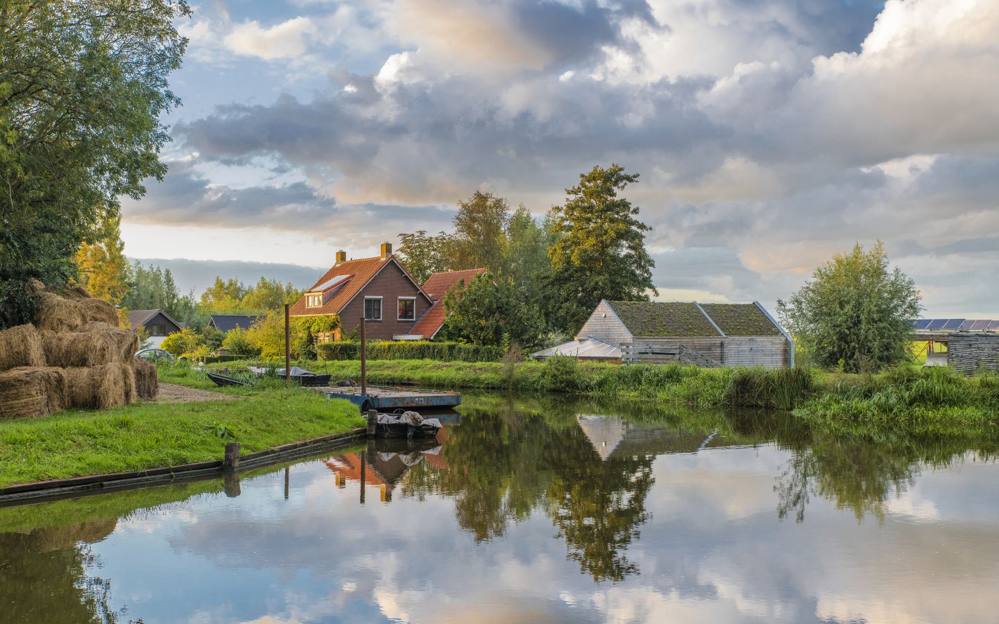 Дома отражаются в реке под небом с белыми облаками