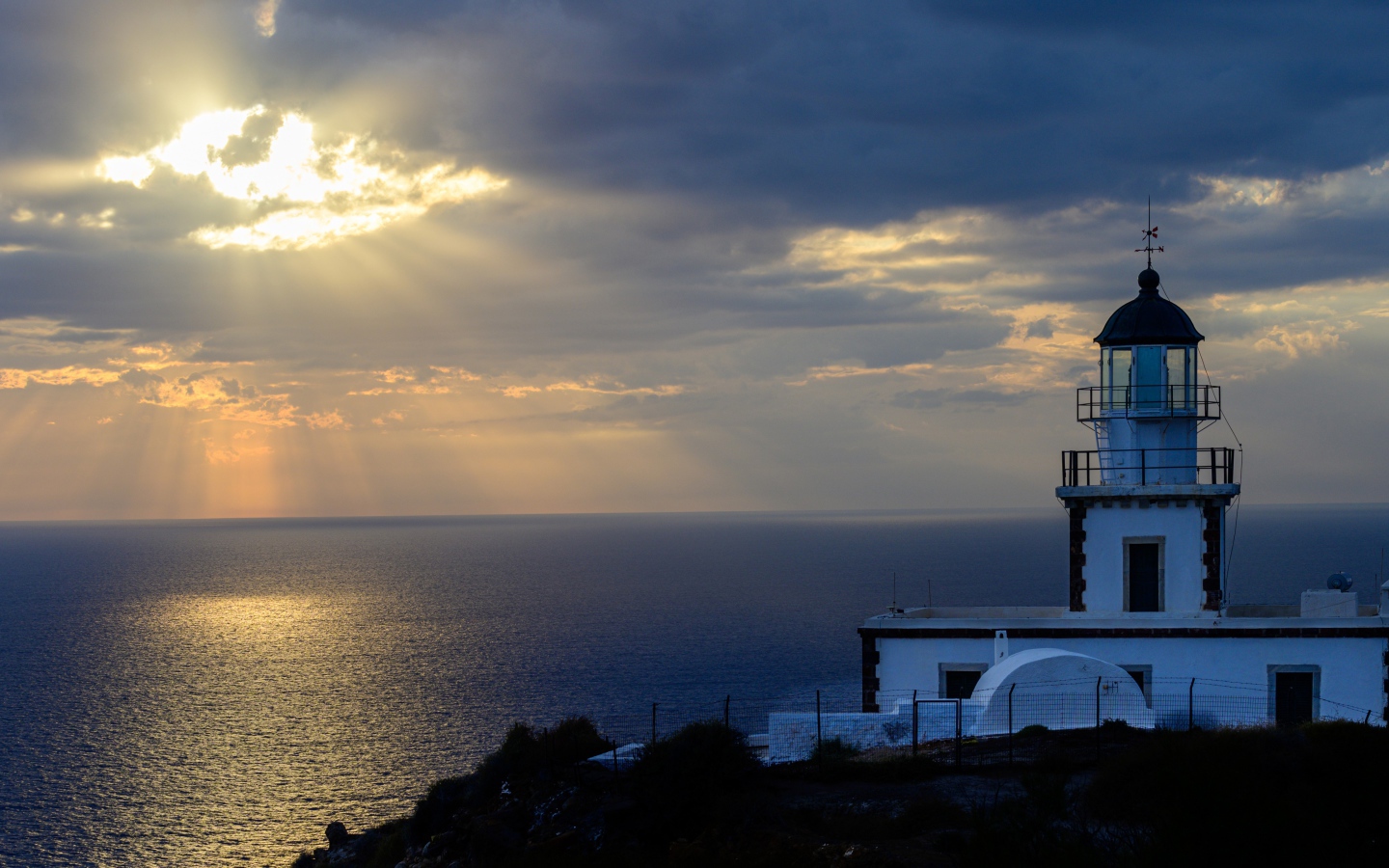 Белый маяк на берегу в лучах солнца у моря 