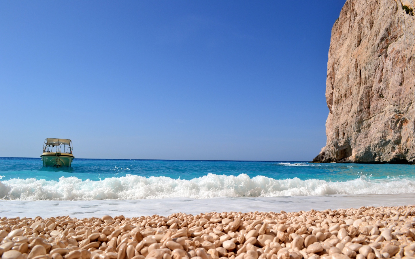 Красивая голубая вода с белыми волнами на пляже с галькой 