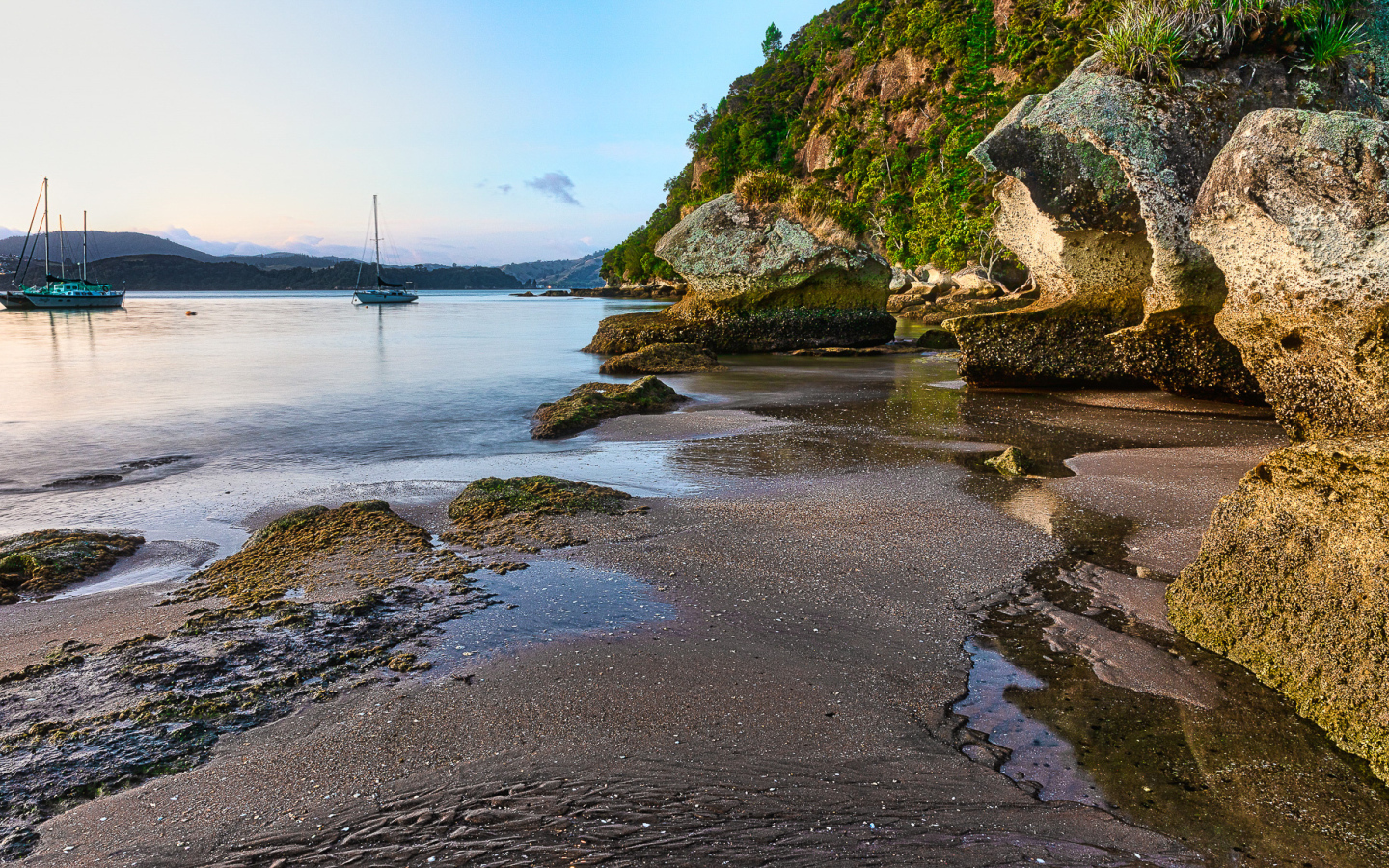 Мокрый песок и большие каменные глыбы на берегу залива