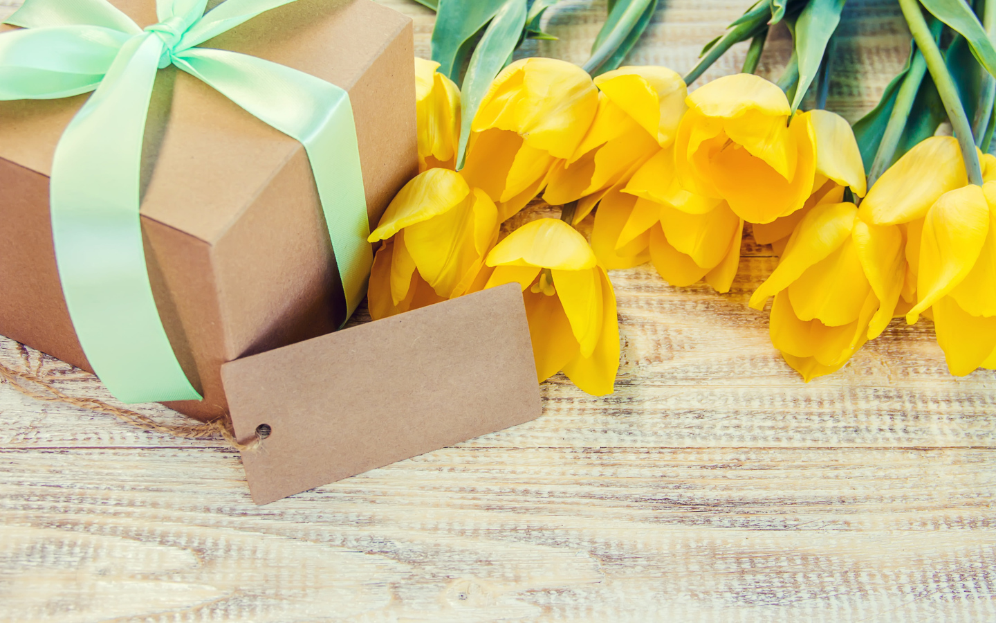 Букет желтых тюльпанов с подарком на столе 