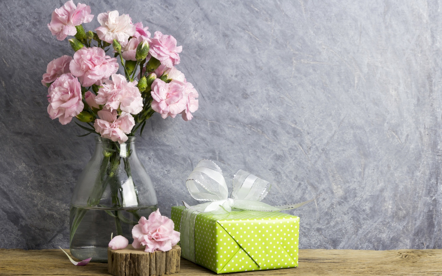 Розовые гвоздики с подарком на сером фоне