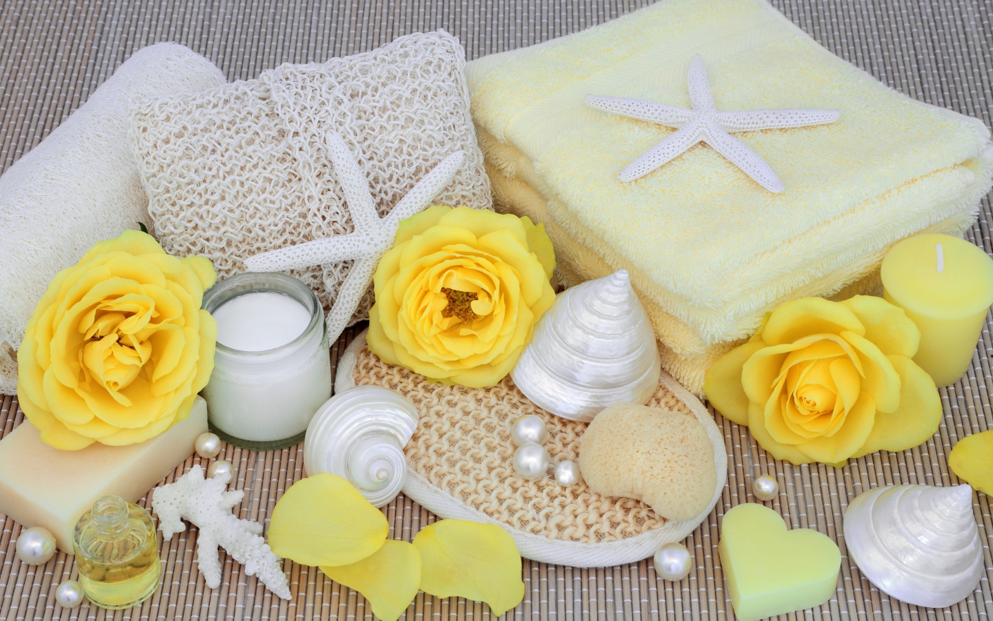 Желтые розы на столе с полотенцем, ракушками и мылом