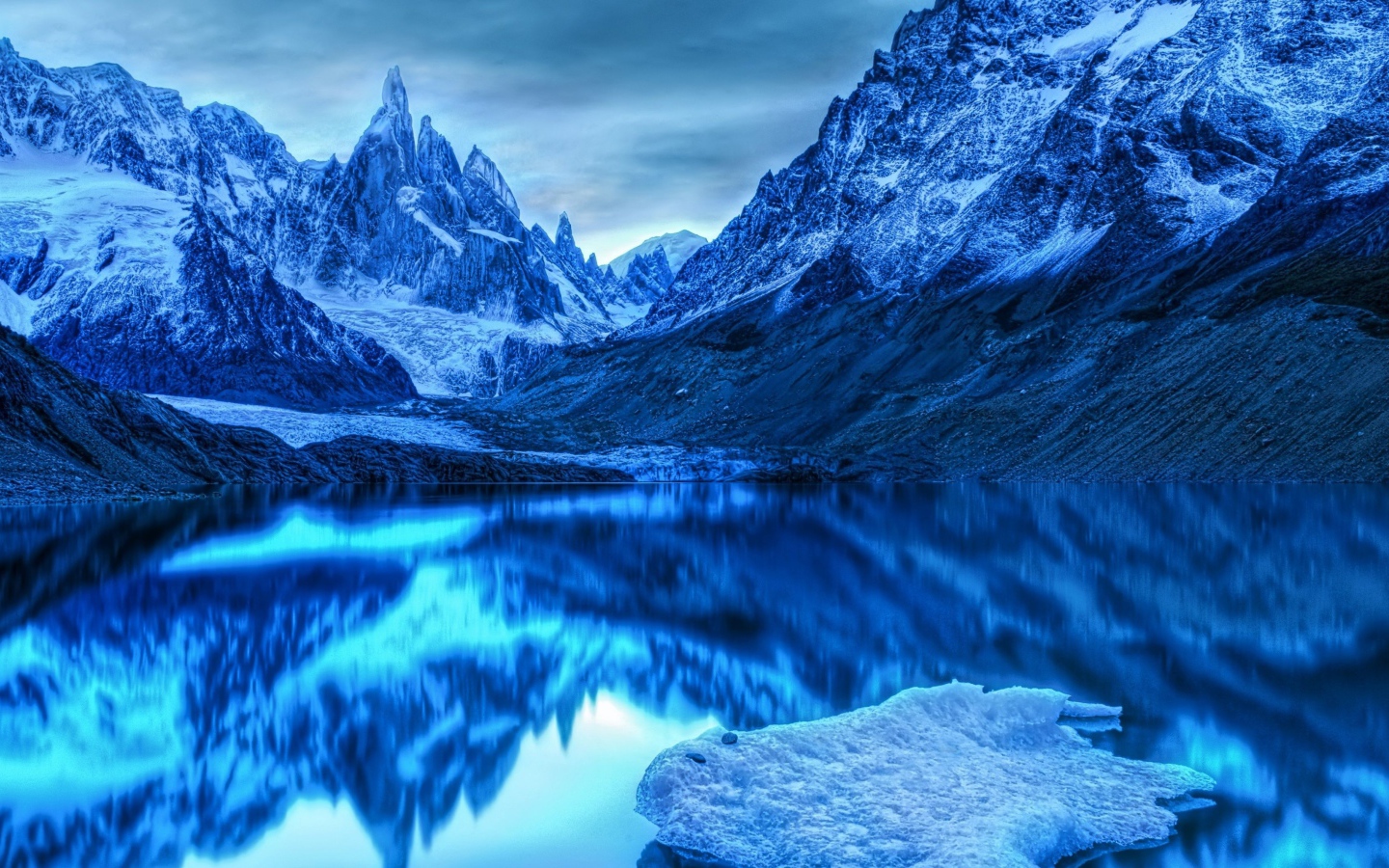 Голубой холодный закат на заснеженными горами у озера 