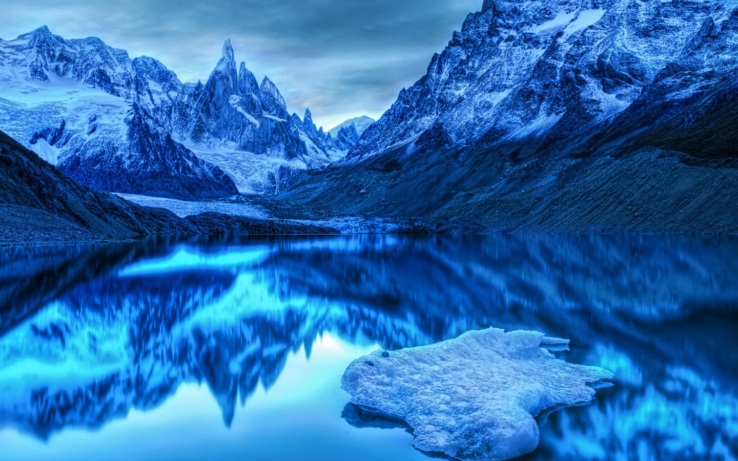 Snow-capped mountains reflected in the water at dusk