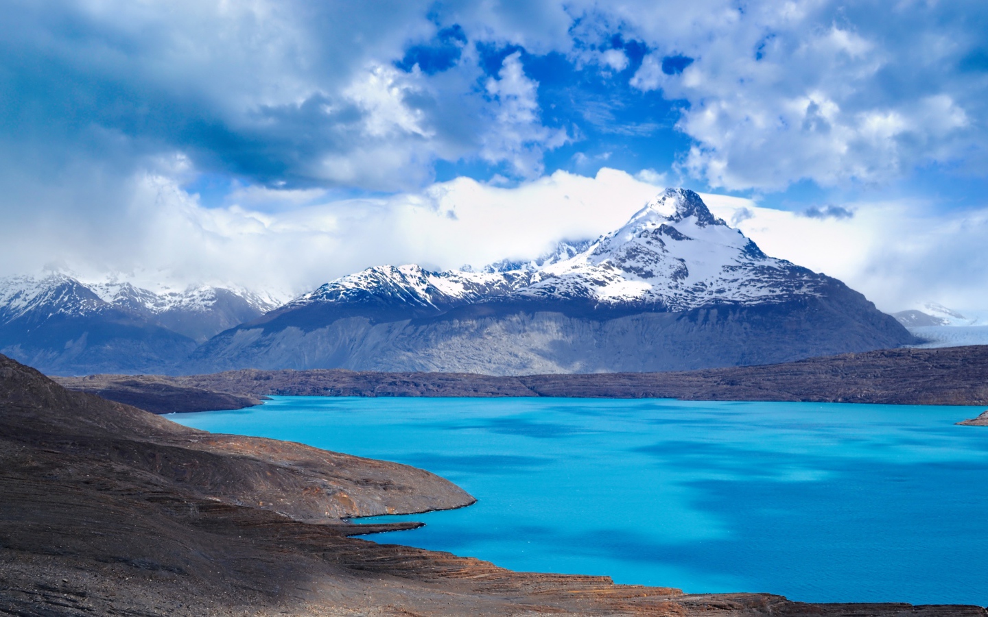 Вид на заснеженную вершину горы у голубого озера 