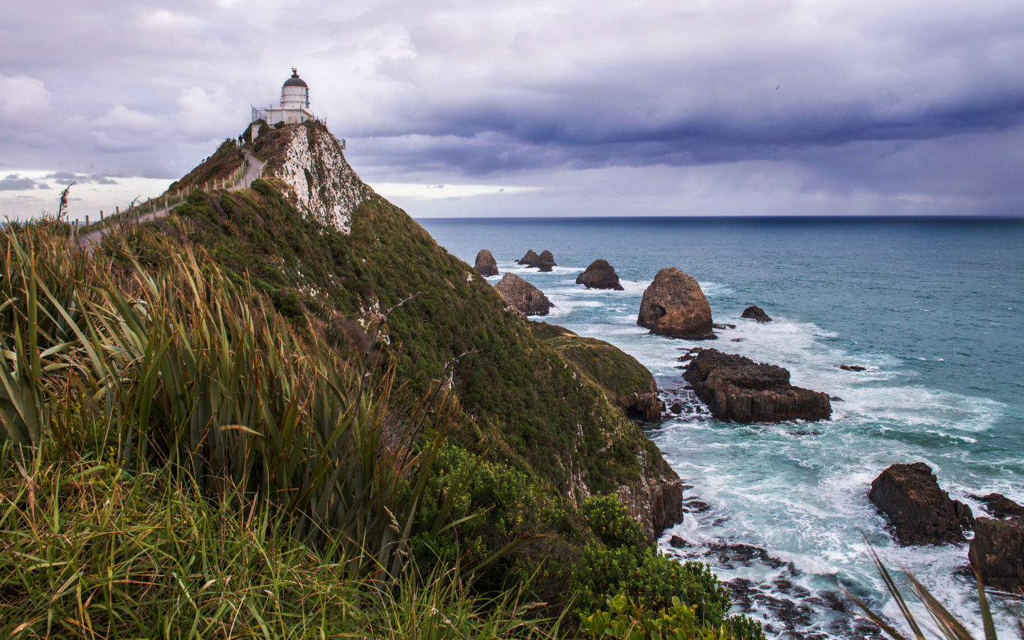 Маяк на вершине утеса у моря под грозовым небом