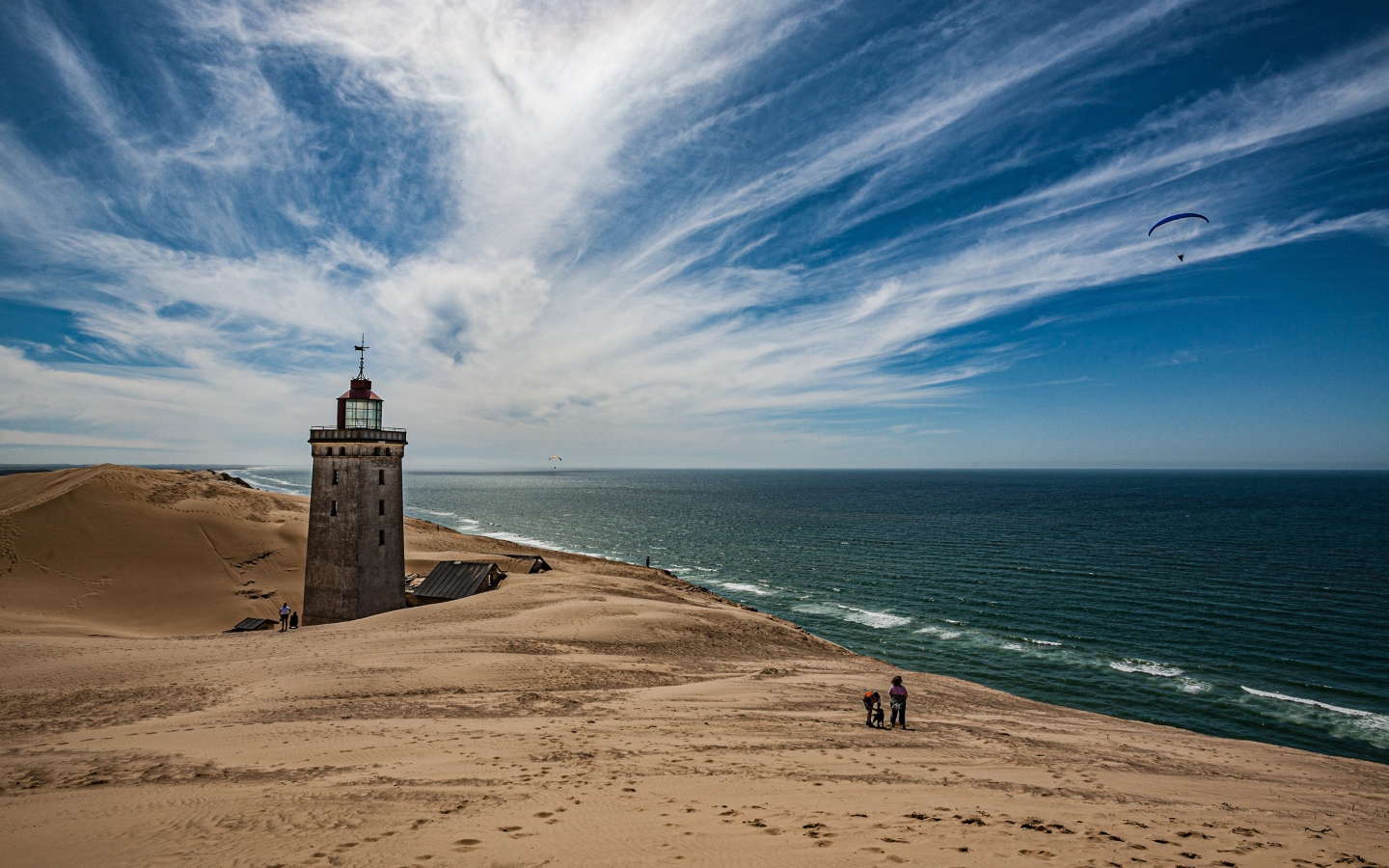 Маяк на песке на берегу моря под голубым небом