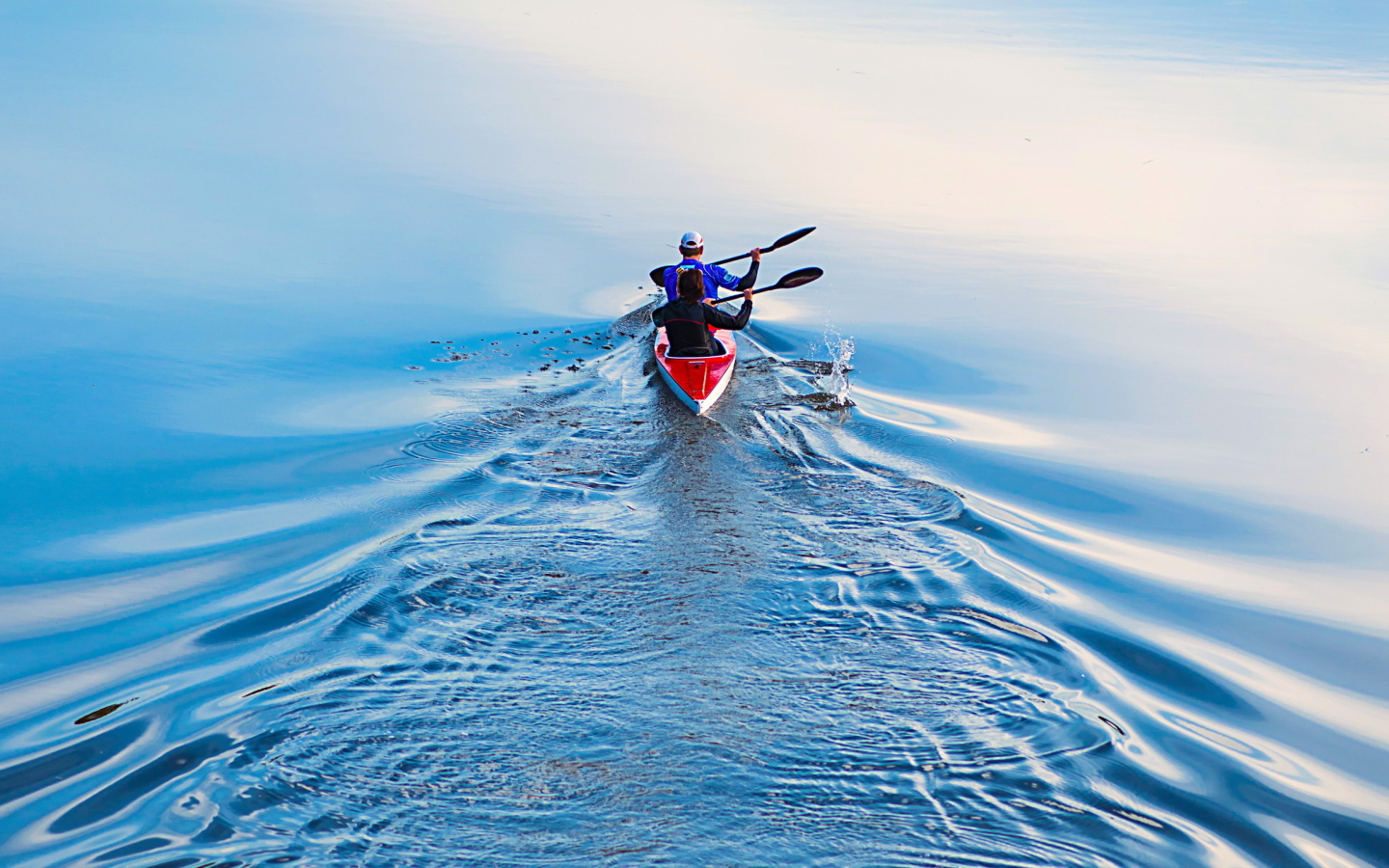 Два спортсмена на лодке плывут по реке 