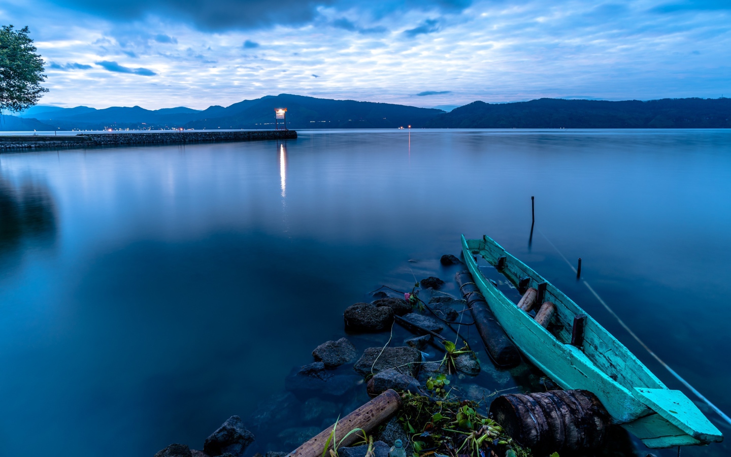Деревянная лодка на берегу тихого озера в сумерках 