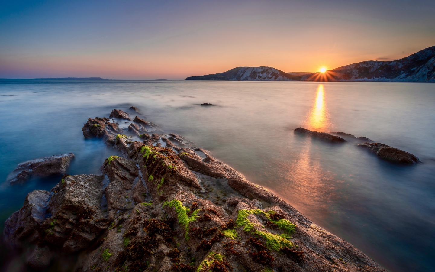 Спокойная вода в море с подводными камнями на закате 