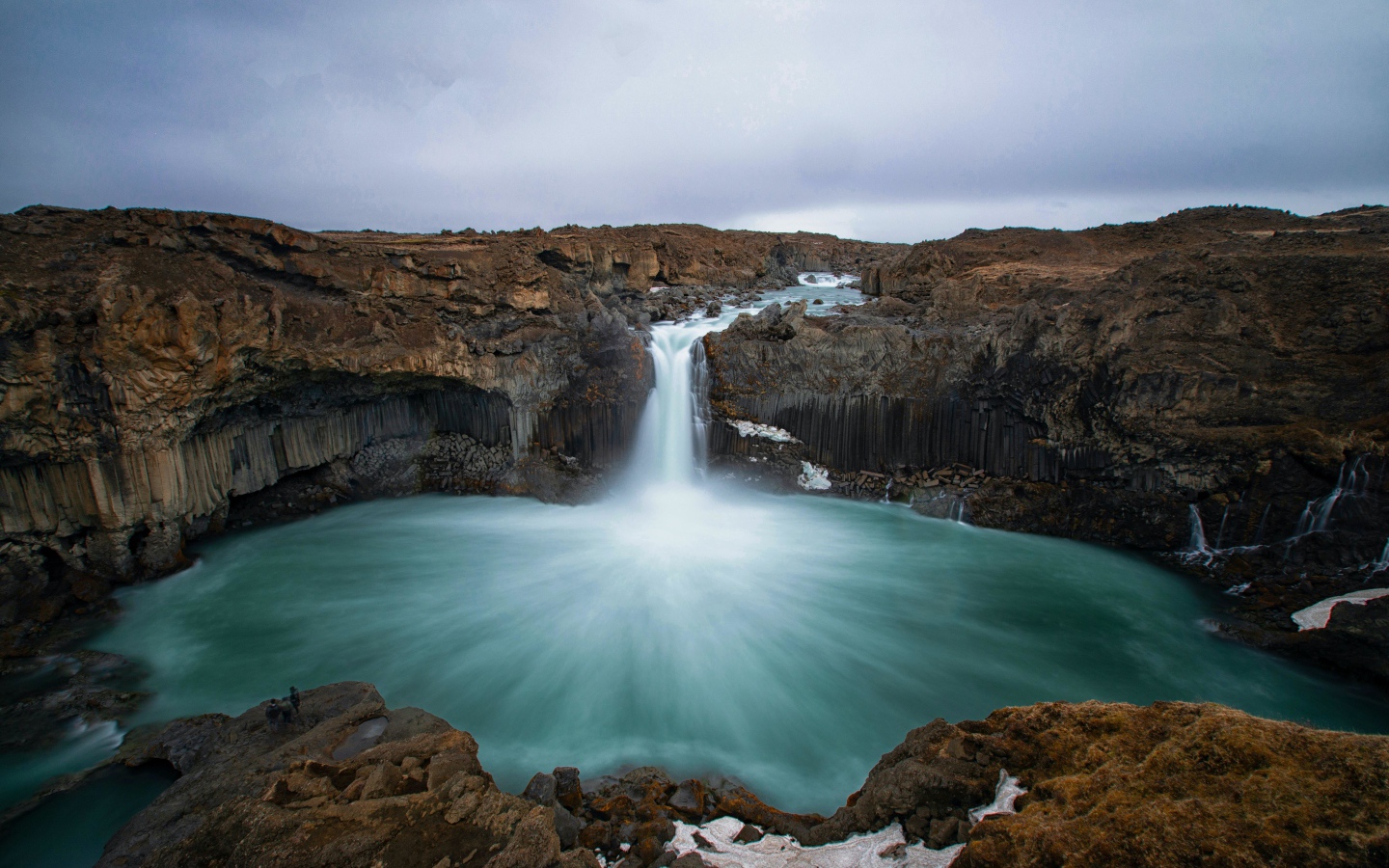 Красивый водопад стекает с каменной скалы в озеро 