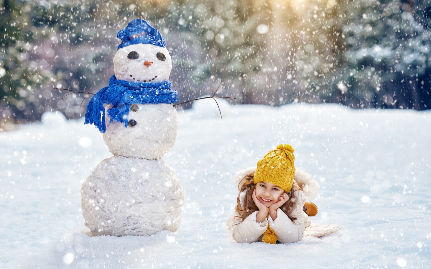 Милая девочка лежит на снегу у снеговика зимой