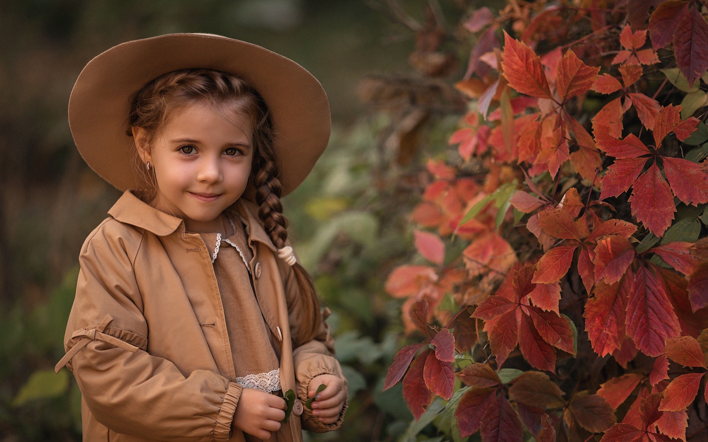 Красивая девочка шляпе стоит у дикого винограда 