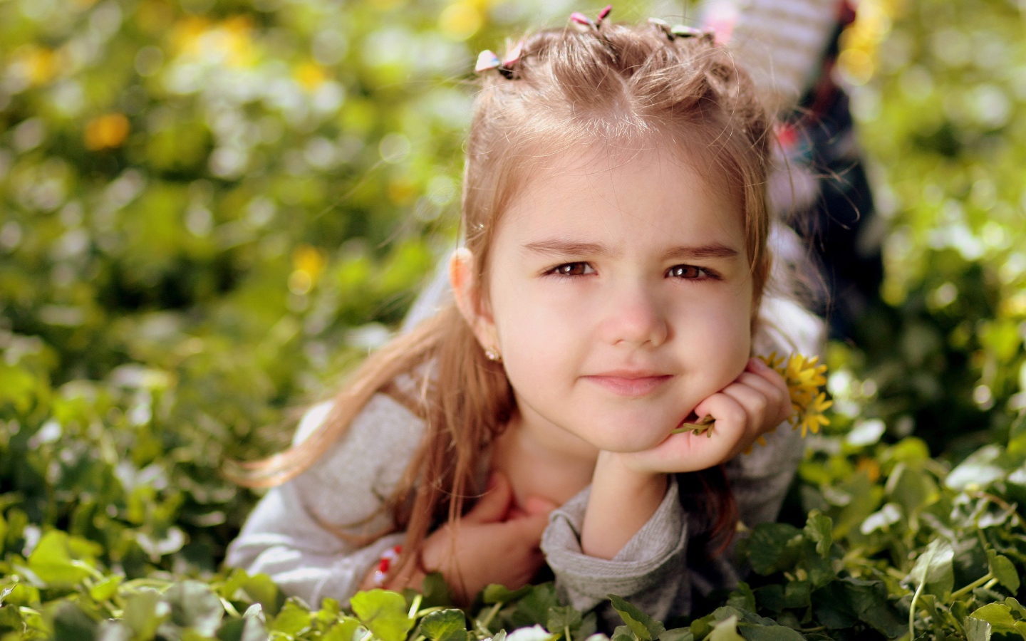 Красивая маленькая кареглазая девочка лежит на траве 