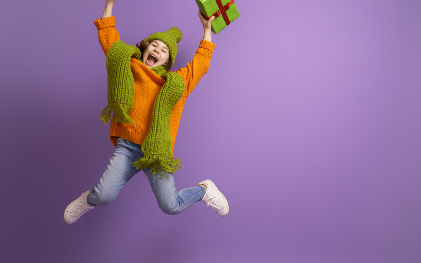 Счастливая девочка с подарком в руке на фиолетовом фоне