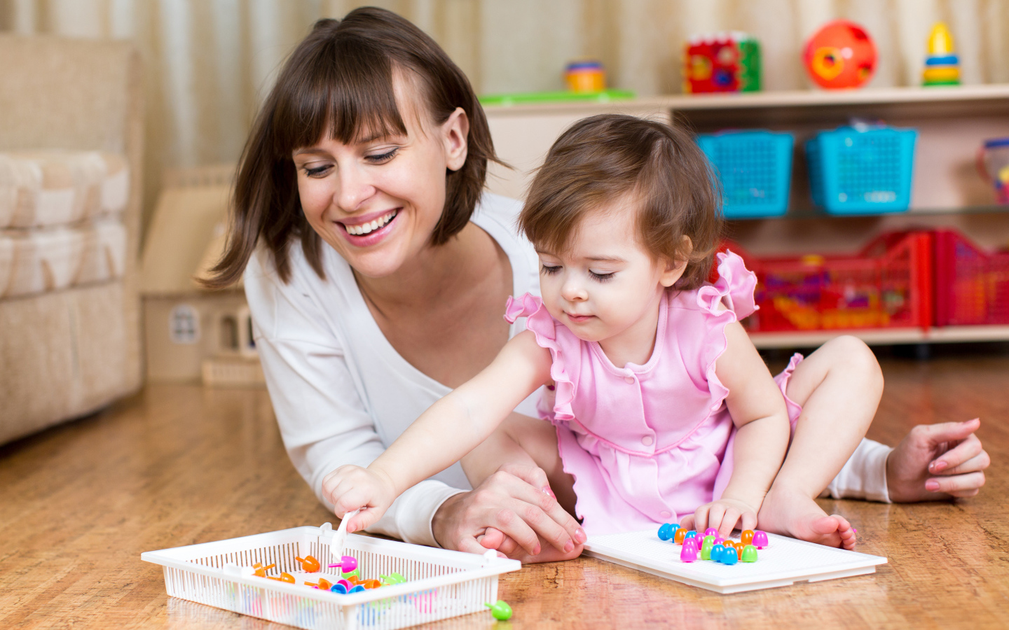 Маленькая девочка в розовом платье играет с мамой