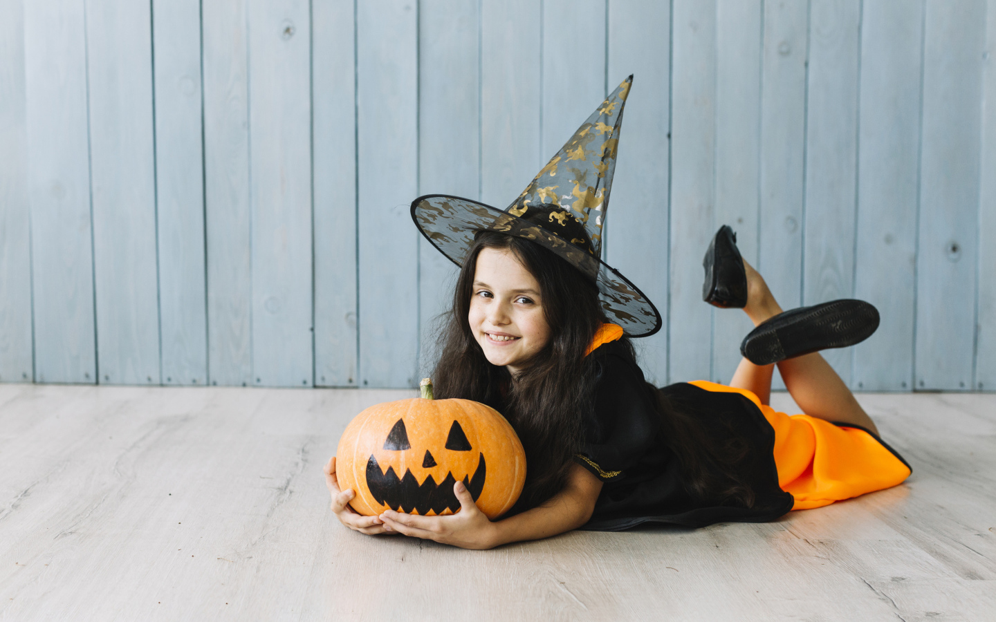 Маленькая девочка в костюме ведьмы с тыквой на Хэллоуин