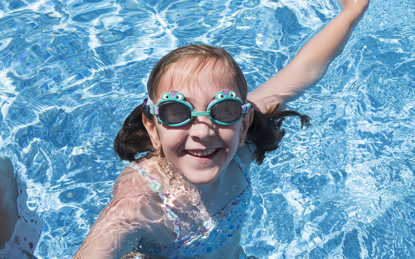 Маленькая улыбающаяся девочка в очках в бассейне 