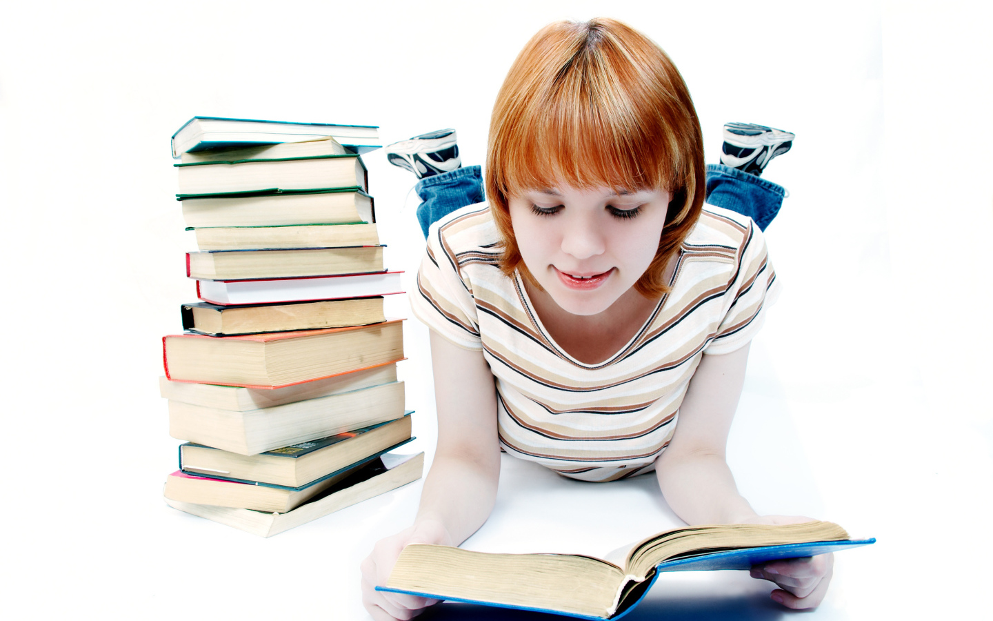 Рыжеволосая девочка школьница читает книги на белом фоне 