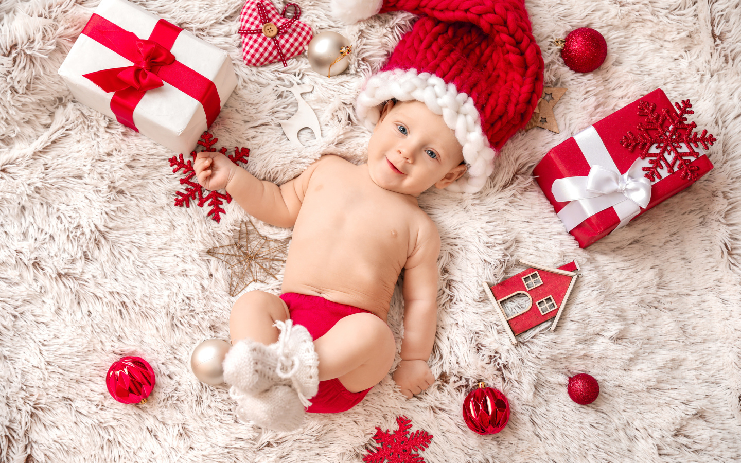 Улыбающийся ребенок  в красной шапке с подарками