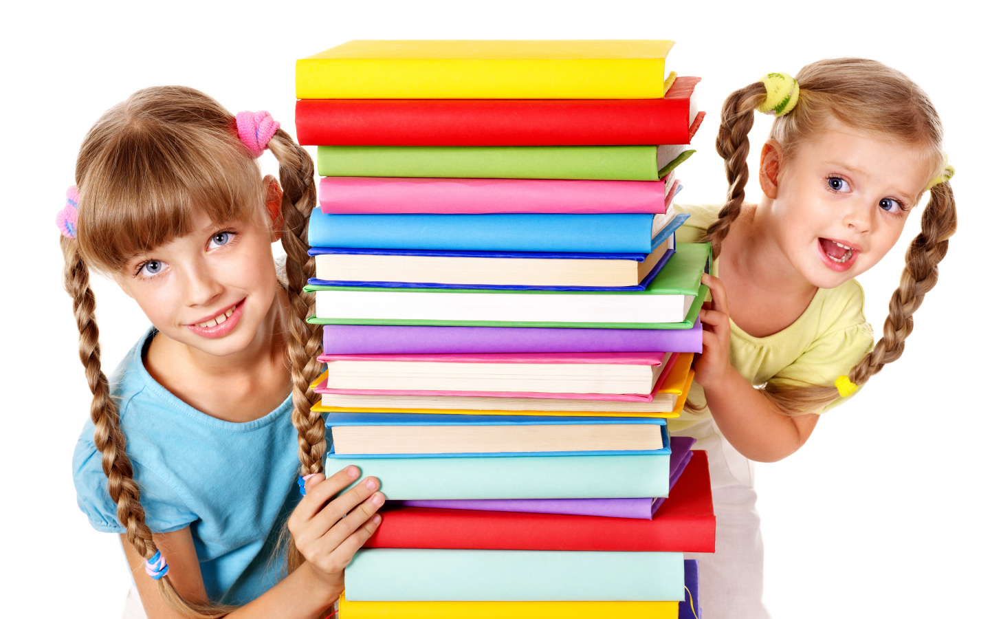 Две маленькие девочки с разноцветными книгами на белом фоне