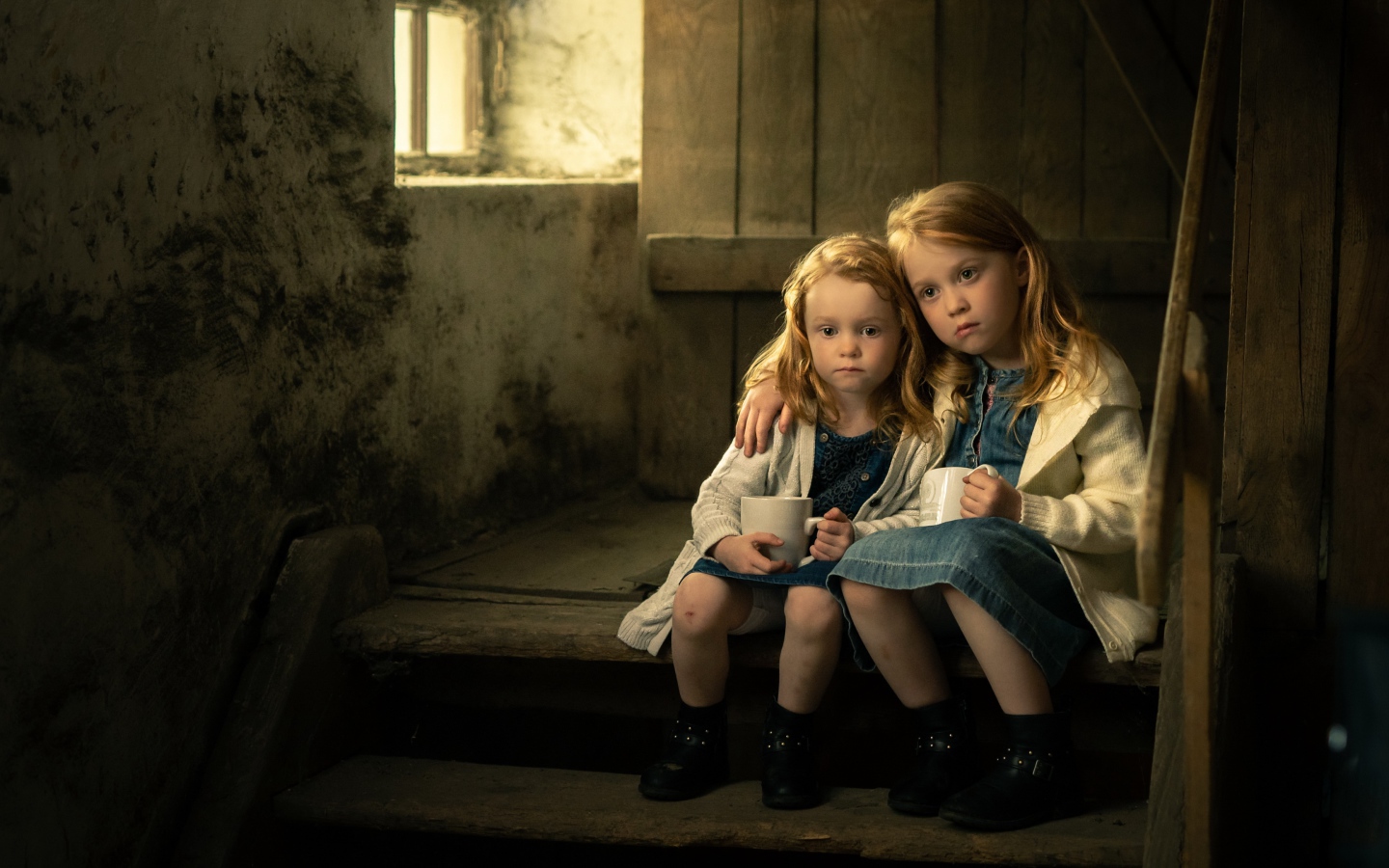 Две маленькие сестры пьют какао на ступеньках дома