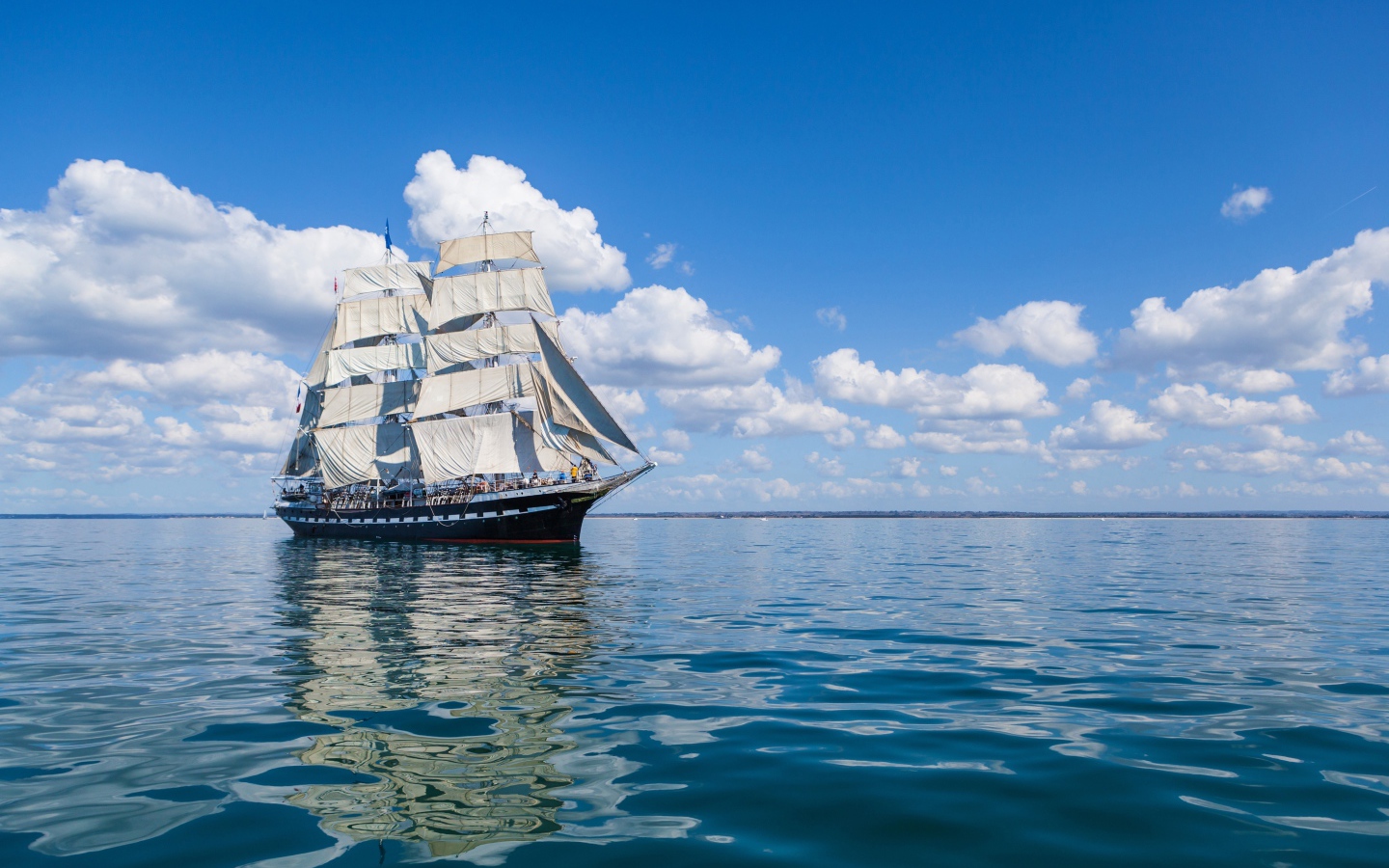 Большой корабль с белыми парусами в море под голубым небом
