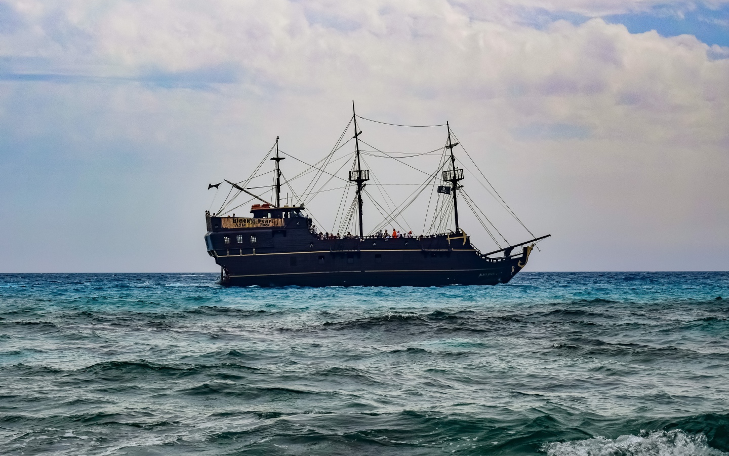 Большой черный пиратский корабль с опущенными парусами в море 