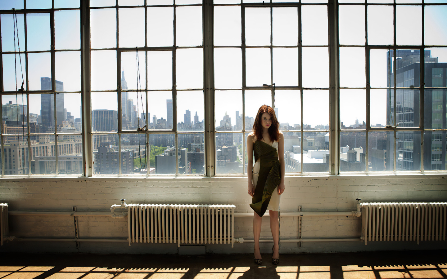 Популярная актриса Эмма Стоун стоит у большого окна