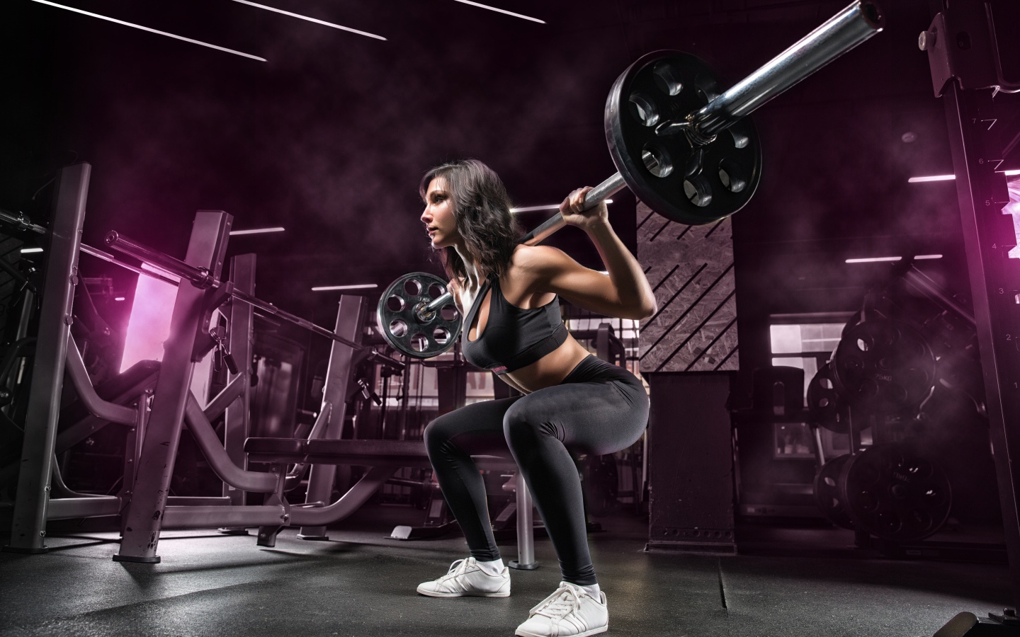 Девушка тяжелоатлет поднимает штангу в спортзале
