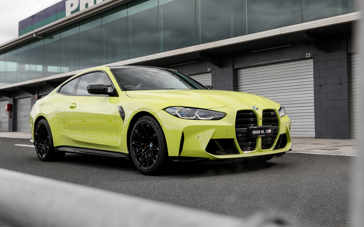 Желтый автомобиль BMW M4 Competition 2021 года у здания