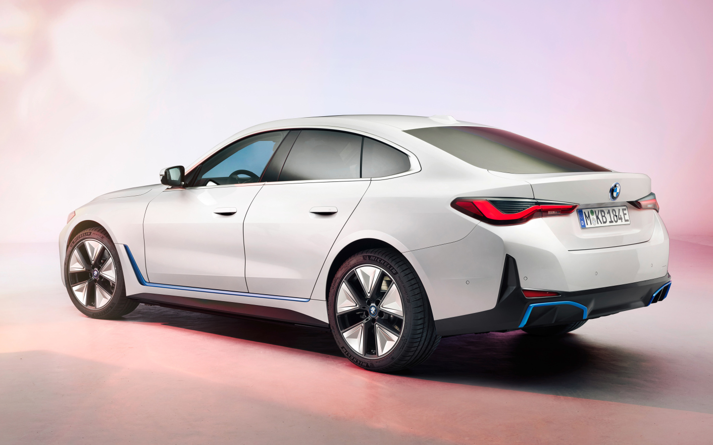 Белый автомобиль BMW I4 2021 года на розовом фоне