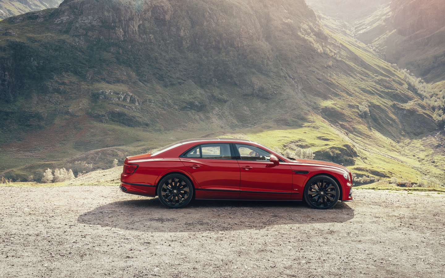 Красный автомобиль Bentley Flying Spur V8 2020 года у горы 