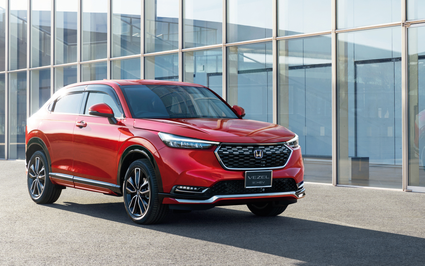 Красный автомобиль Honda Vezel EHEV 2021 у здания