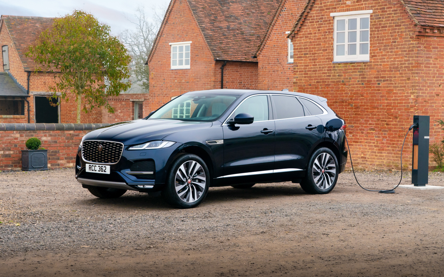 Черный дорогой автомобиль Jaguar F-Pace P400e AWD 2021 года, на заправке