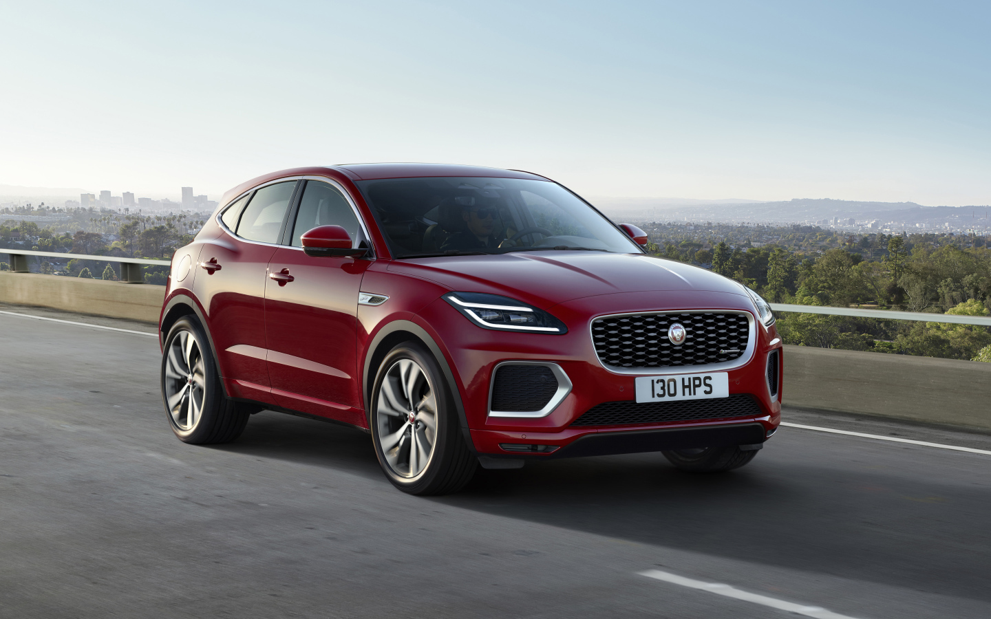 Красный автомобиль Jaguar E-Pace R-Dynamic 2021 года на мосту