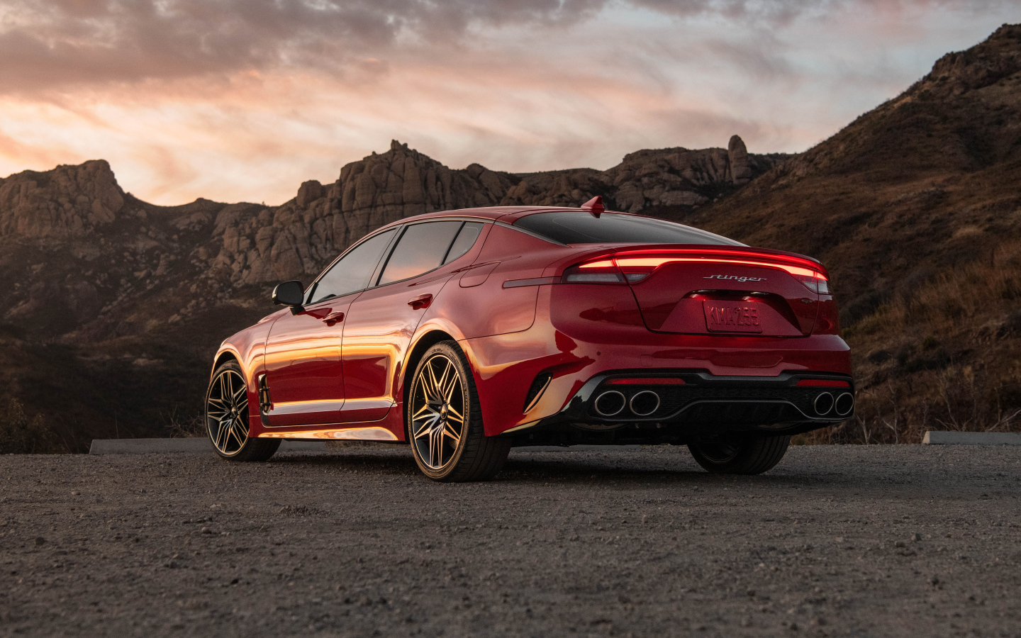 Красный автомобиль Kia Stinger GT, 2022 года в горах вид сзади