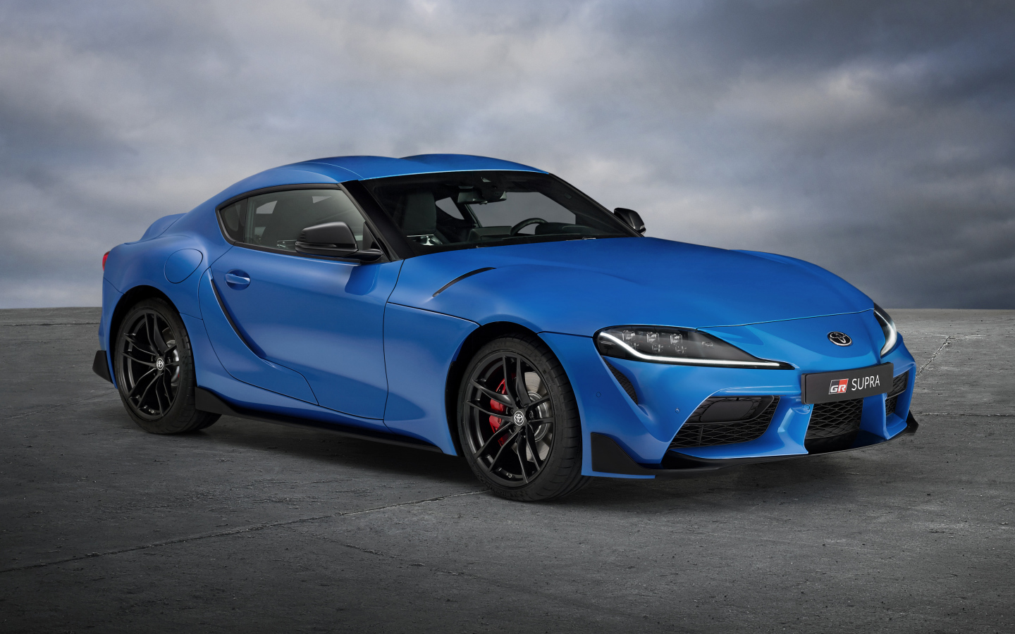 Синий автомобиль Toyota GR Supra, 2021 года на сером фоне