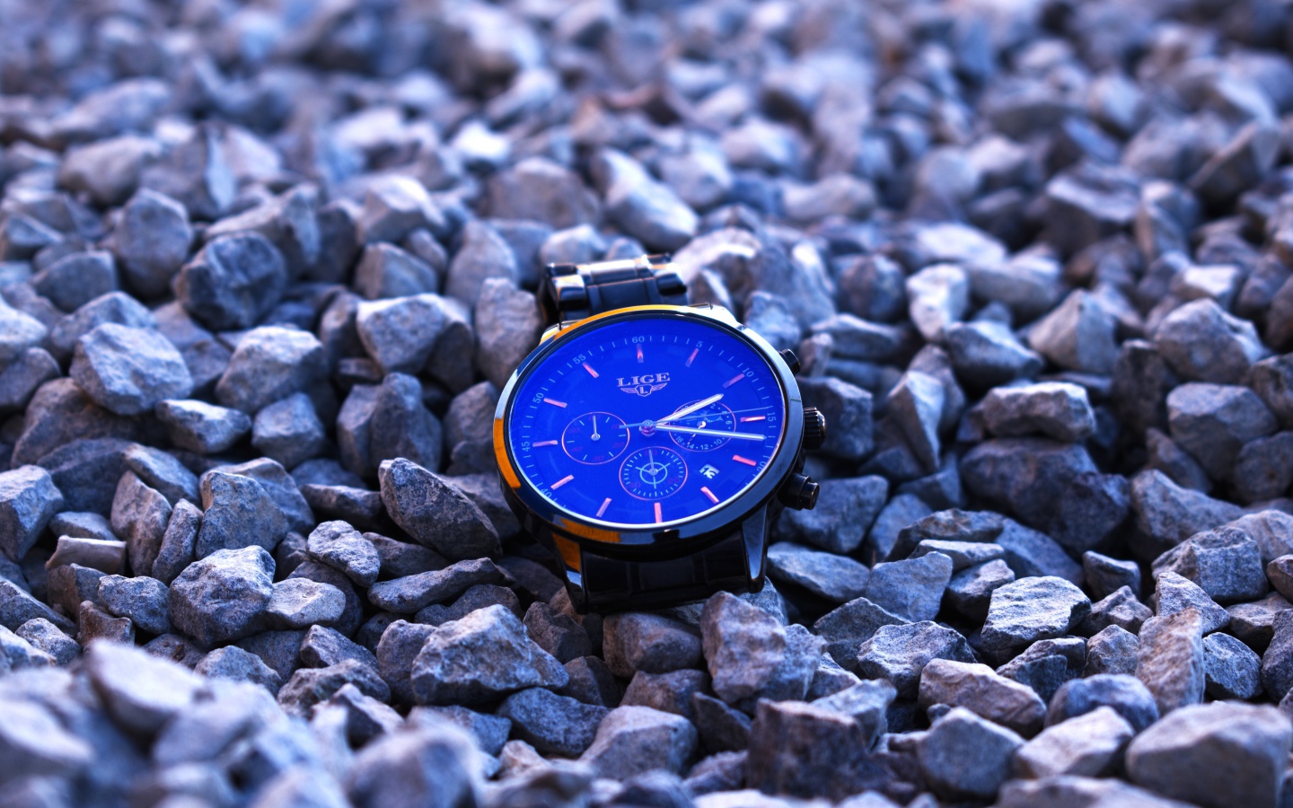 Голубые наручные часы лежат на камнях