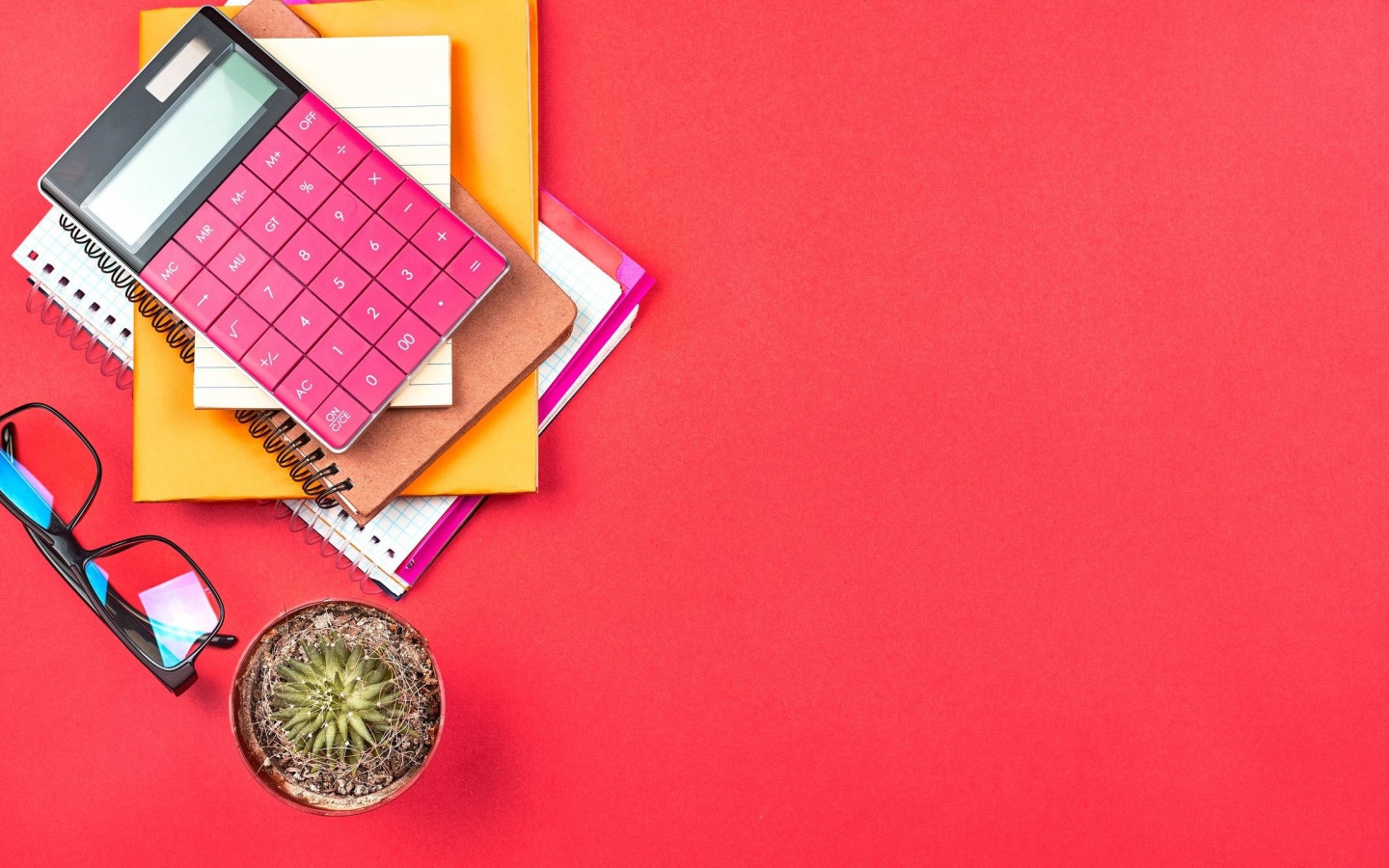 Калькулятор с очками и блокнотами на розовом фоне 