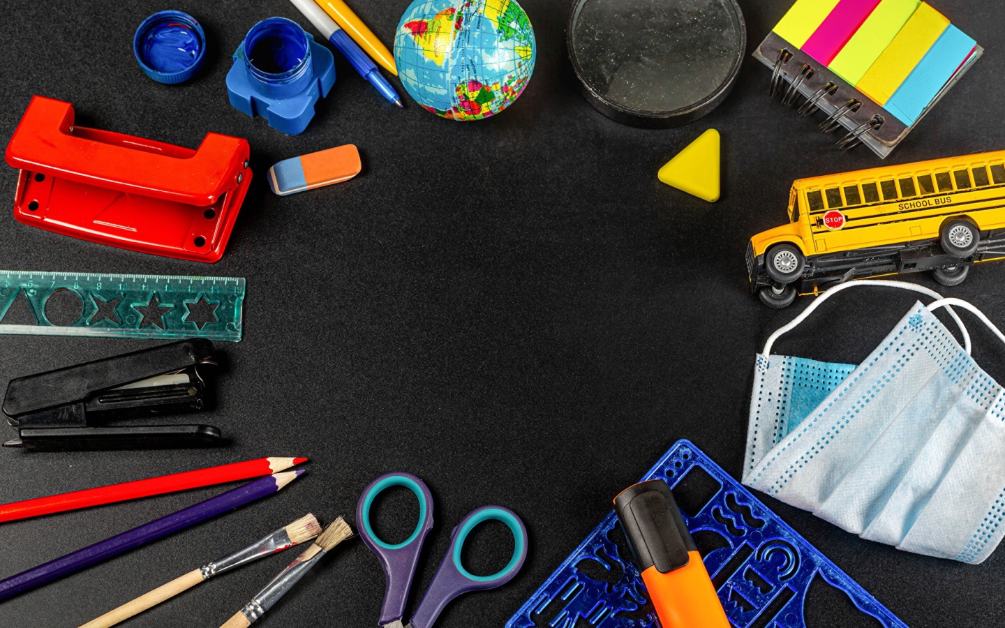 Канцелярские предметы, игрушки и маска на черном столе 