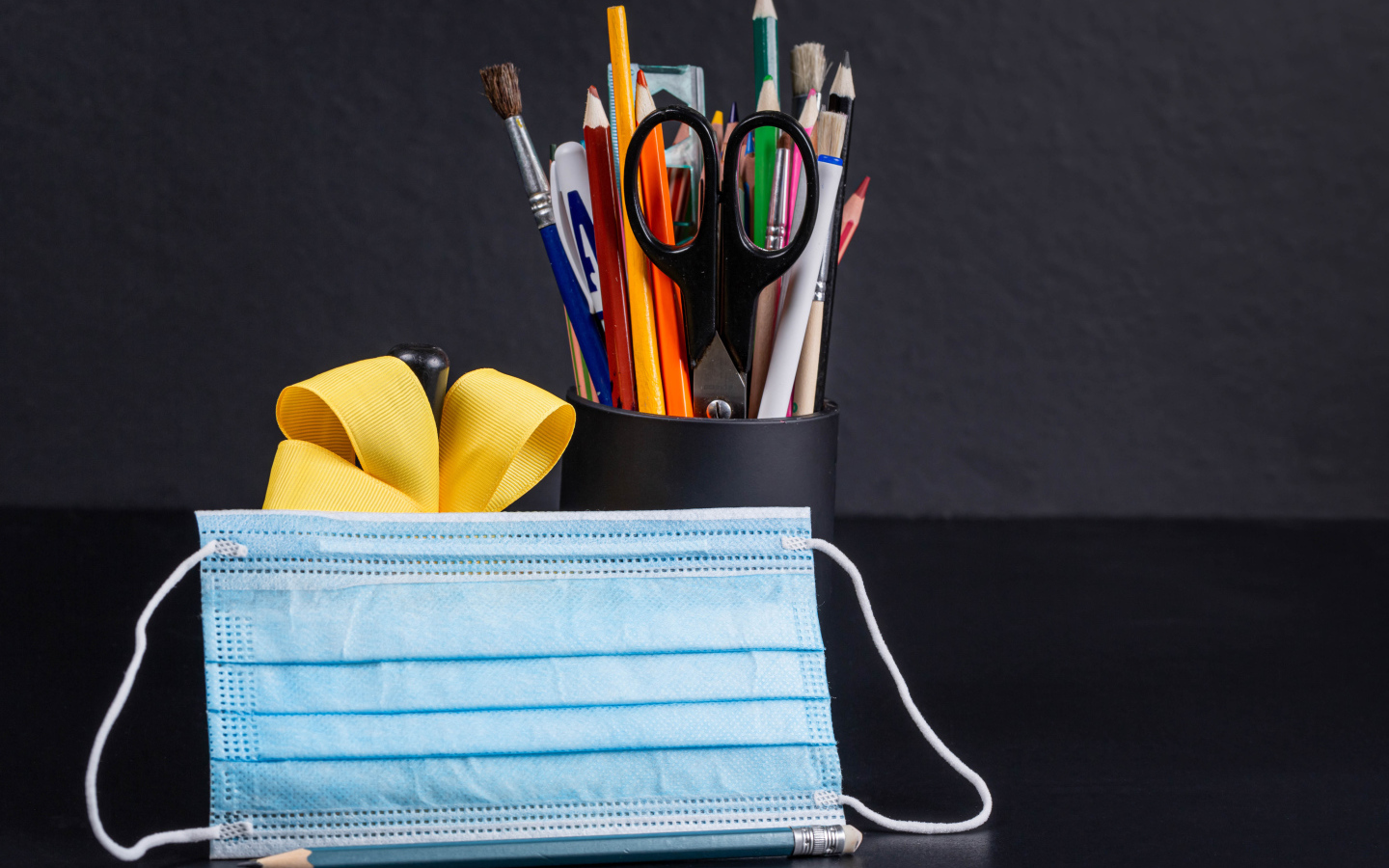 Канцелярские предметы на столе с медицинской маской